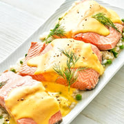 Salmon dish with yellow sauce and green herbs on a white plate.