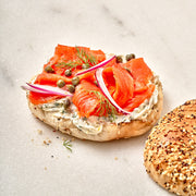 Bagel with smoked salmon, cream cheese, onions, and capers on a light background.