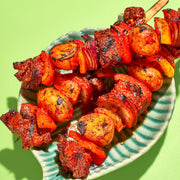 Skewers of grilled meat and vegetables on a green background