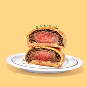 Cut in half meat pie on a plate with a yellow background