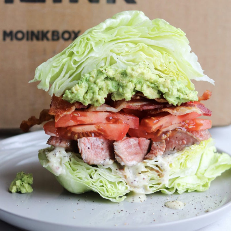 Stacked salad with lettuce, steak, and tomato on a plate.