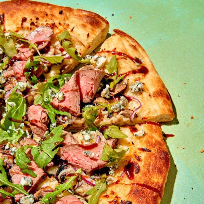Pizza with meat and green toppings on a green background