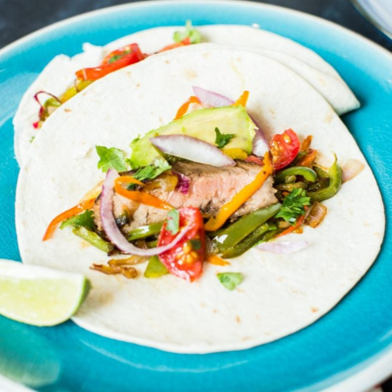 Tortilla with sliced meat and vegetables on a blue plate