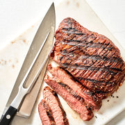 Grilled steak with slices cut on a marble board with a knife.