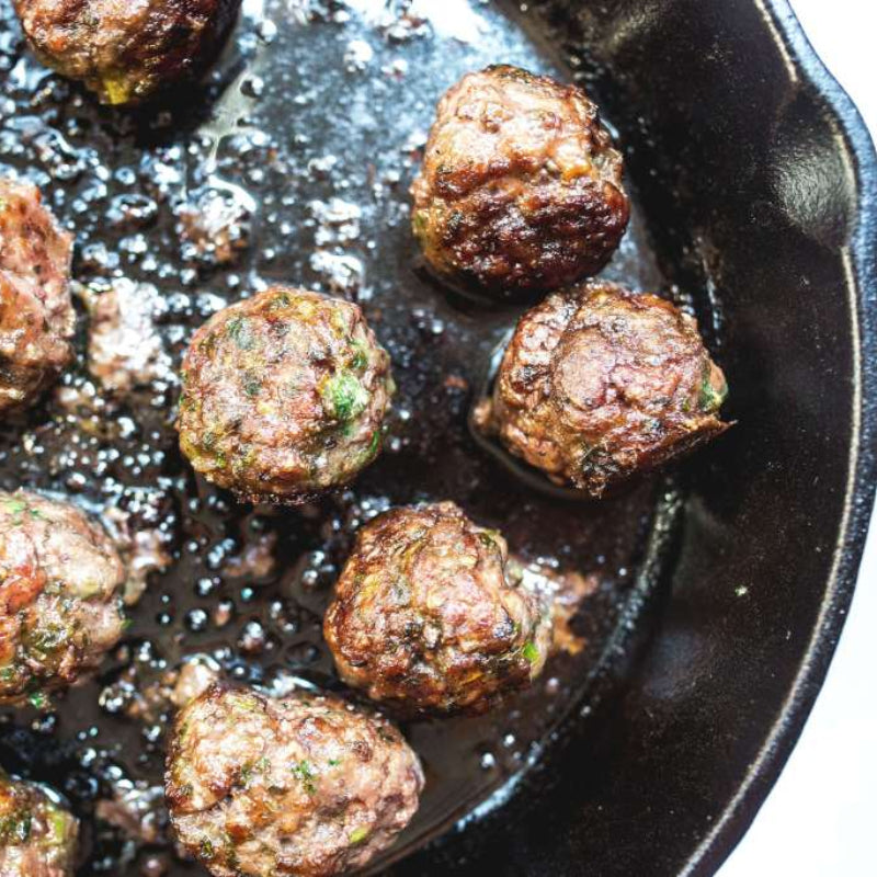 Browned meatballs in a cast iron skillet.