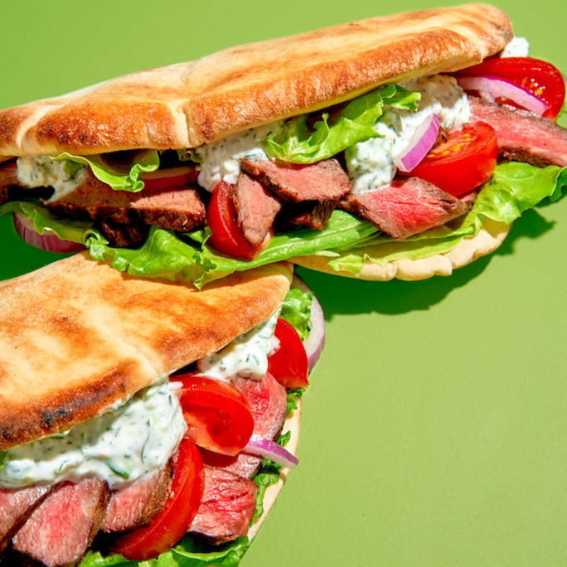 Submarine sandwich with beef, lettuce, and tomato on a green background