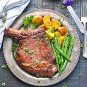 Steak dinner with potatoes and vegetables on a metal plate.