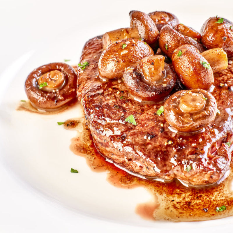 Steak & mushrooms in a rich brown sauce on a white plate