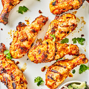 Grilled chicken drumsticks with a side of salad on a white plate