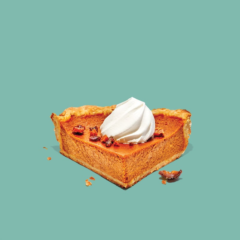 Slice of pumpkin pie with whipped cream on a teal background