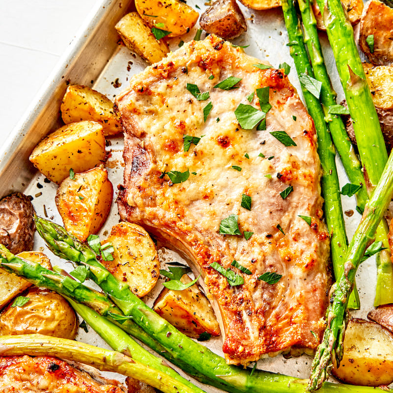 Sheet pan with pork chops, asparagus, and potatoes.