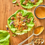 Lettuce wraps with ground meat and vegetables on a wooden surface.