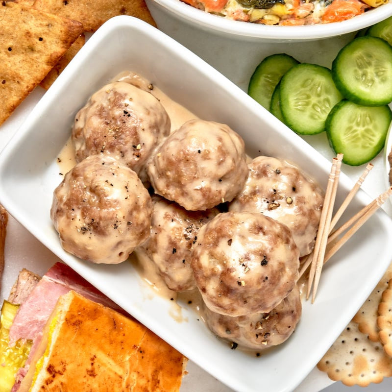 White dish with meatballs and toothpicks on a snack platter.