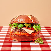 Hamburger with lettuce and cheese on a checkered tablecloth with a plain background