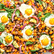 Sheet pan with sweet potato hash, eggs, and vegetables.