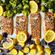 Salmon fillets with lemon and vegetables on a baking tray.