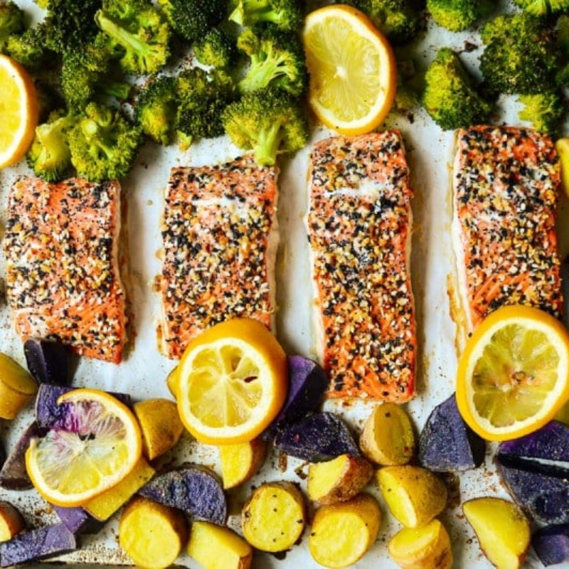 Salmon fillets with lemon and vegetables on a baking tray.