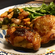 Plated dish with roasted chicken, vegetables, and salad on a decorative plate.